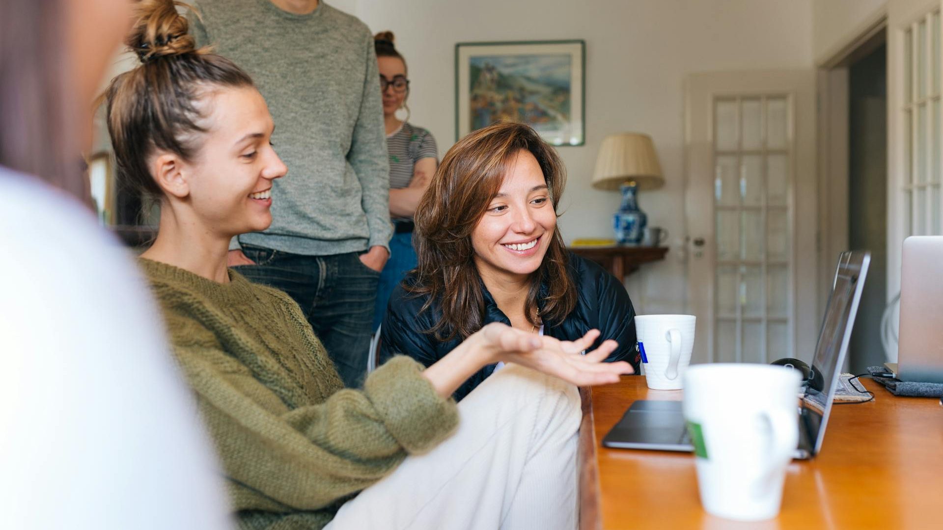 group of adults at home chatting around a laptop