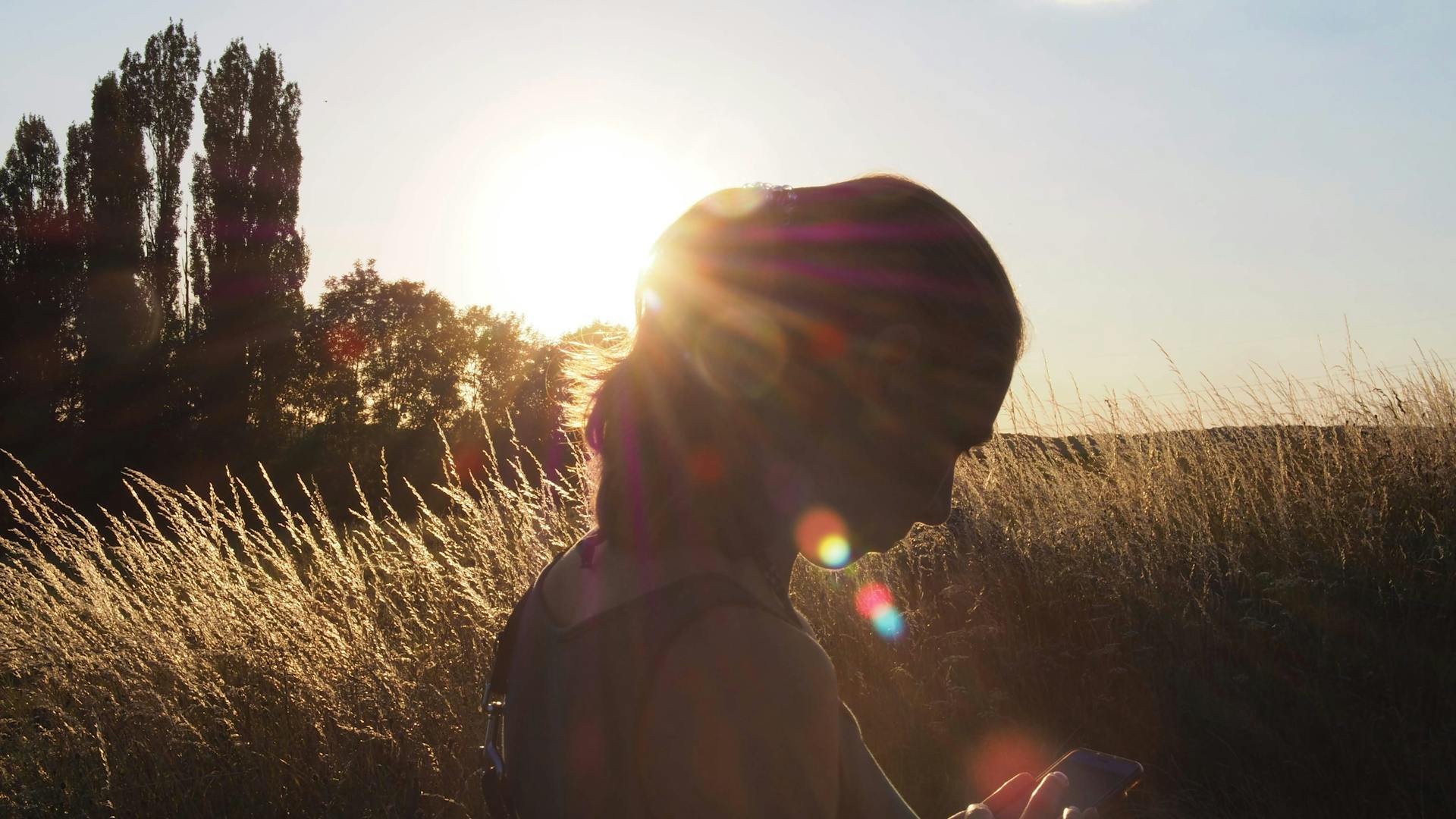 silhouette of a woman in front of the sun in a field