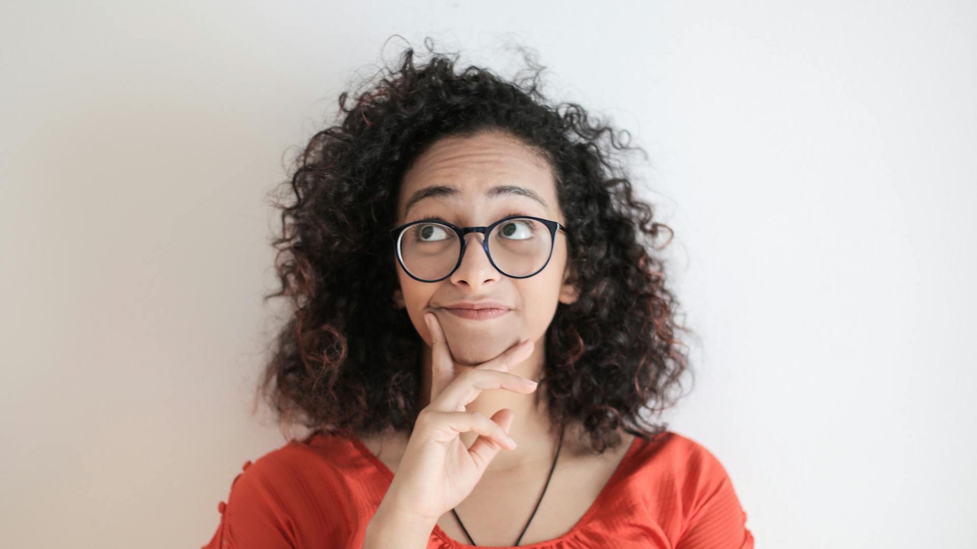 thinking woman wearing glasses and orange top